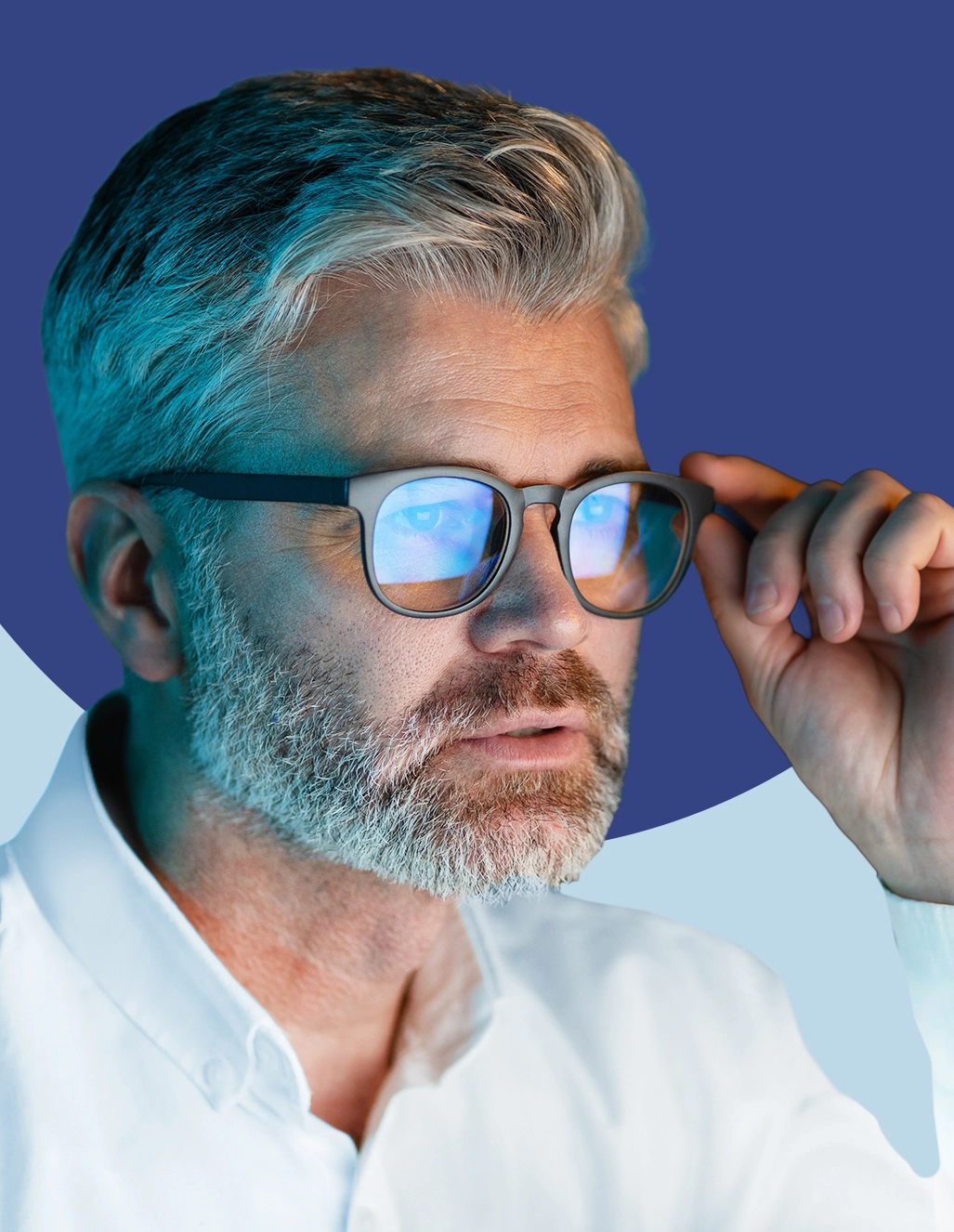 Close-up of a man with salt-and-pepper hair wearing blue-light filtering eyeglasses, hand adjusting the frame, on a blue two-tone background.